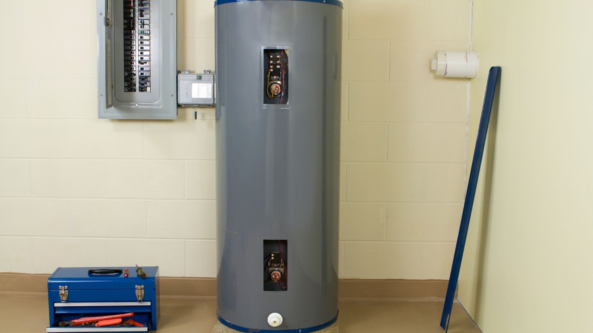 Large gray water heater with electrical panel in utility room